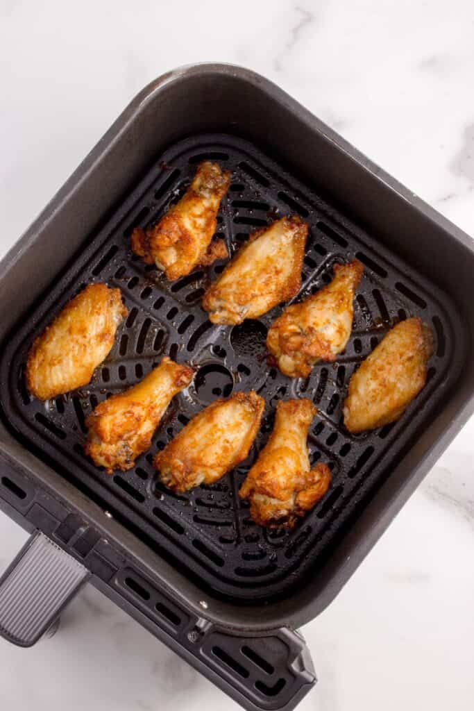 Crispy cooked chicken wings in an air fryer basket.