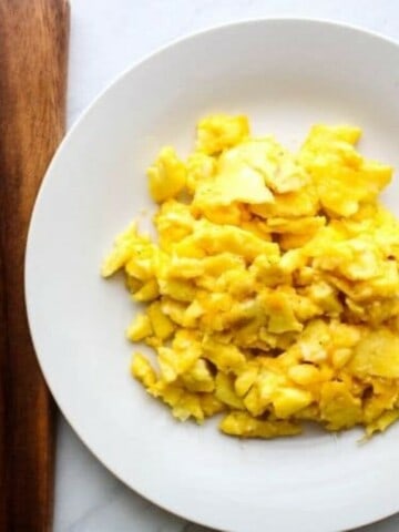 Scrambled Eggs on a white plate with fork to the side