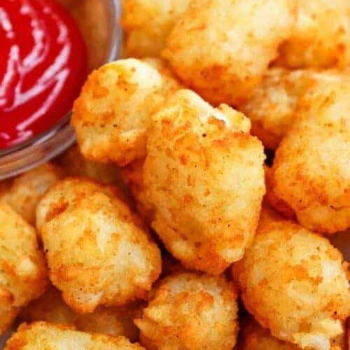 Closeup of Air Fryer Tater Tots with bowl of ketchup peaking into the top left