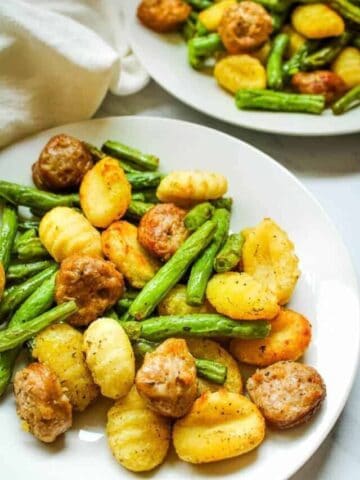 Sausage, Gnocchi, and Green Beans on a white plate