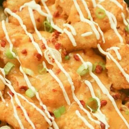 Air Fryer Totchos in pan with sour cream drizzled on top