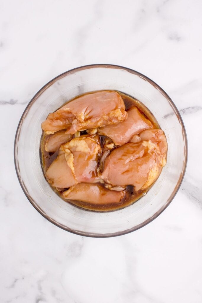 Marinating chicken thighs in a glass bowl.