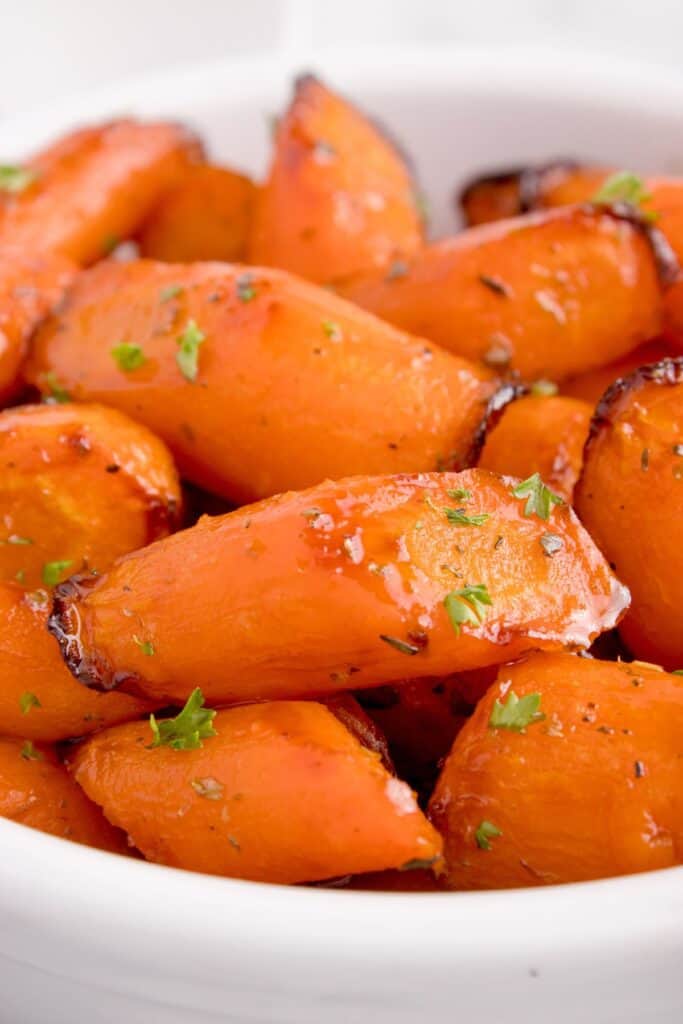 Close up of cooked air fryer carrots inside a white bowl.