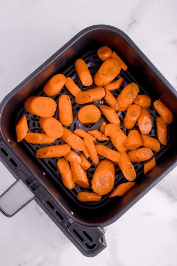 Raw cut carrots in an air fryer basket ready to be cooked.