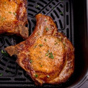 close up of cooked pork chops in an air fryer basket