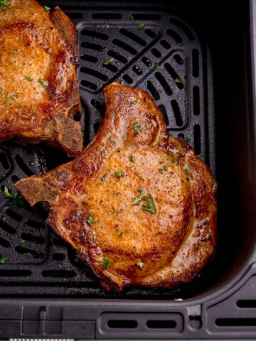 close up of cooked pork chops in an air fryer basket