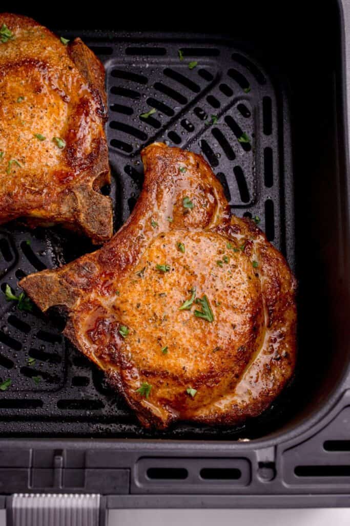 close up of cooked pork chops in an air fryer basket