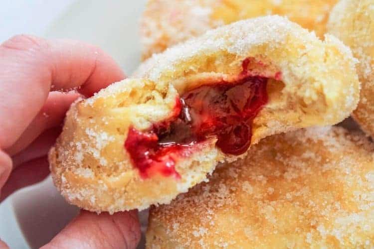 Air Fryer Jelly Donuts bitten into and hand holding it up
