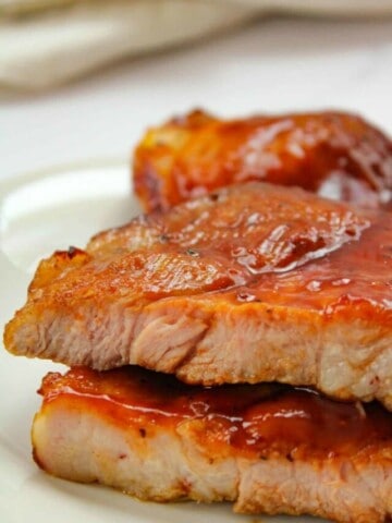 Air Fryer Pork Butt Steaks with BBQ sauce on a white plate cut open