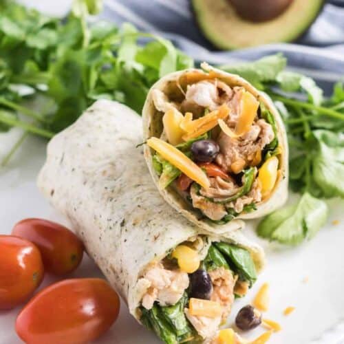 BBQ chicken wrap cut in half and stacked on top of each other served on a lunch plate with grape tomatoes.