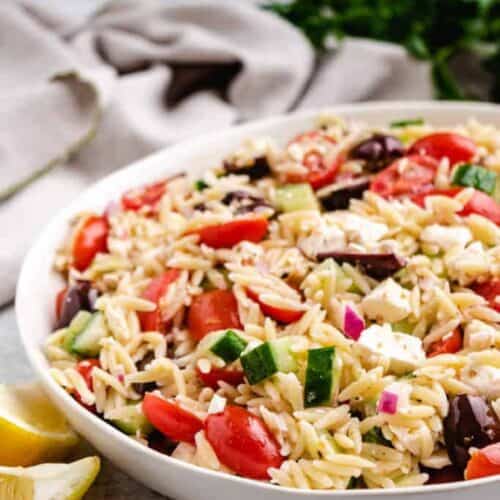 Greek orzo salad in a white bowl.