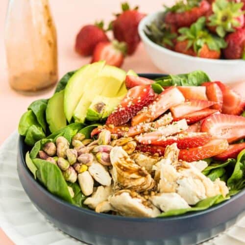 Strawberry salad with chicken in a bowl with sliced avocado.