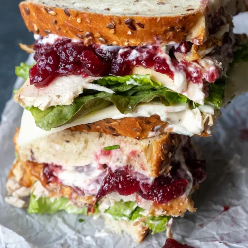 Close up of cranberry turkey sandwich with two slices stacked on top of each other.