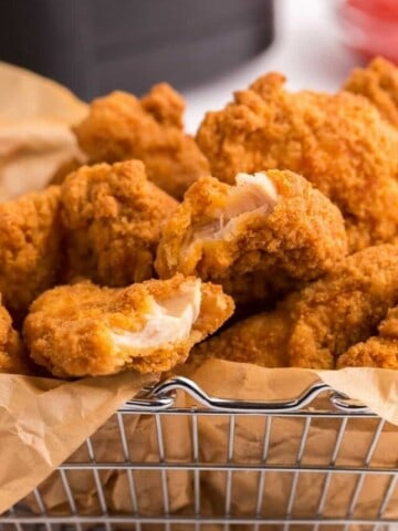 Closeup of chicken tenders in a wire basket with parchment paper