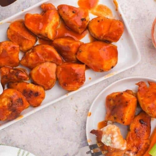 Air Fryer Boneless wings on a rectangle serving plate and some on a plate with fork inside one of the wings