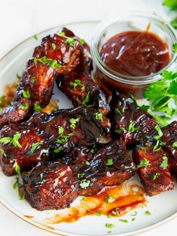 air fryer country style ribs coated in bbq sauce on a white plate.