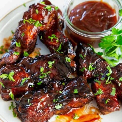 air fryer country style ribs coated in bbq sauce on a white plate.