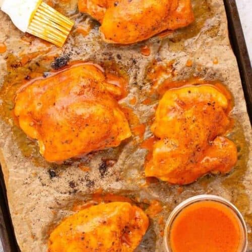 buffalo chicken thighs on cooking pan with parchment