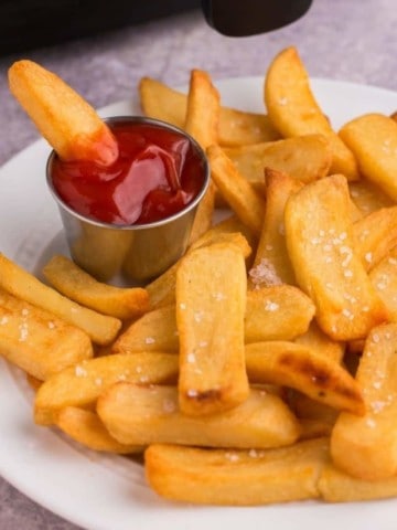 Golden and crispy air fryer steak fries on plate with dipping sauce