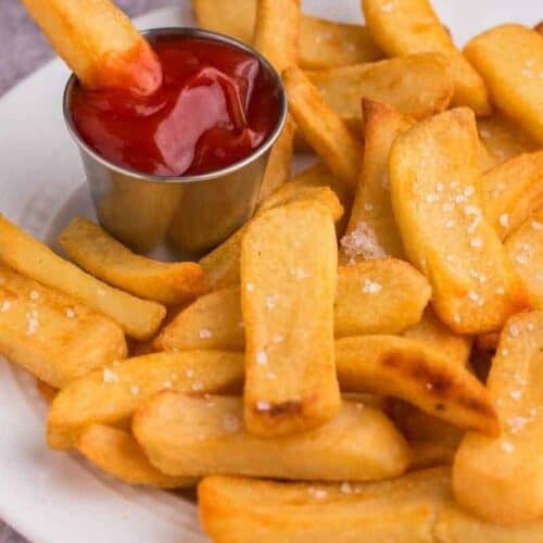 Golden and crispy air fryer steak fries on plate with dipping sauce