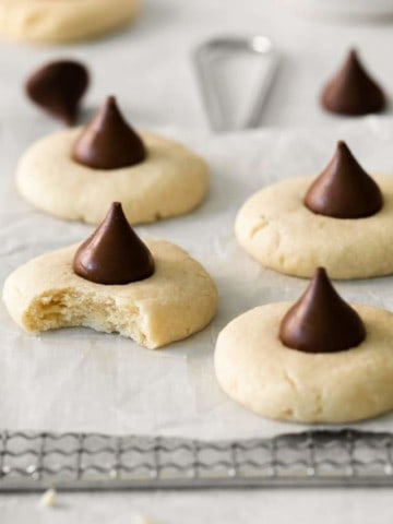 Several sugar cookies topped with hershey kisses on parchment paper