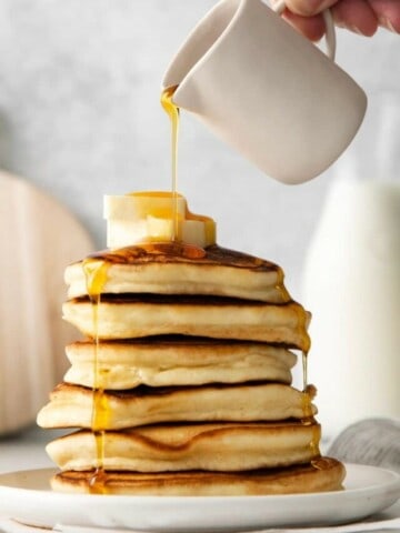 adding syrup to pancakes