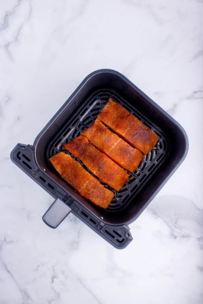 Raw salmon in an air fryer basket.