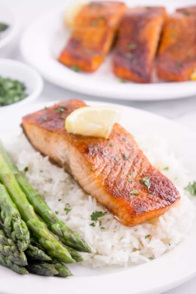 Air fryer salmon filet served with a lemon wedge on top of rice.