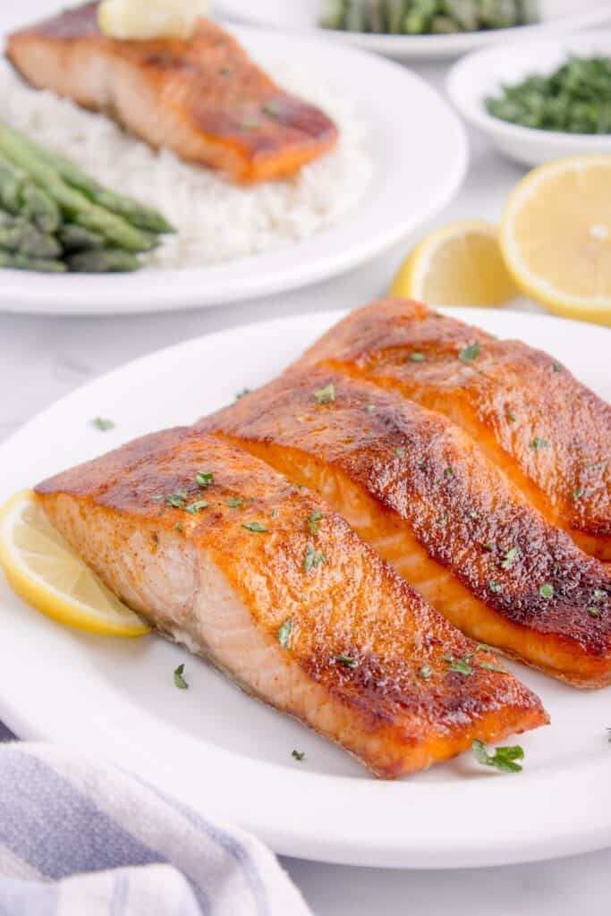 air fryer salmon filets on a white plate served with lemon.