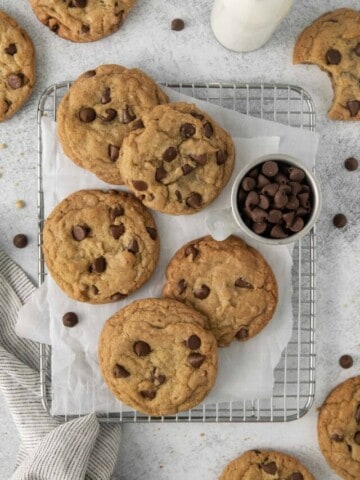 Chocolate Chip Cookies lying flat on a cooling rack with a sheet of parchment paper beneath them.