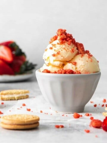 Strawberry Crunch Topping on vanilla ice cream in an off white bowl.