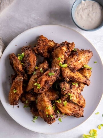 Overhead view of chicken wings prepared in the air fryer on a white plate.