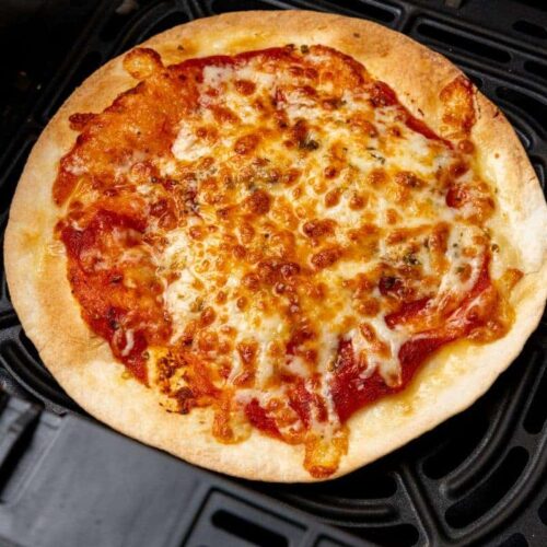 Tortilla pizza prepared in an air fryer resting in a black basket.