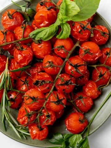 Seasoned air fried cherry tomatoes resting on a green serving plate.