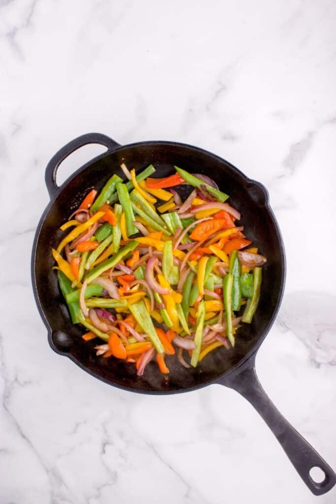 peppers and onions sauteed in a cast iron skillet.