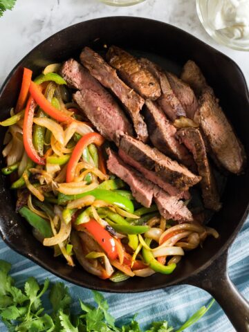 beef steak fajitas in a cast iron skillet.