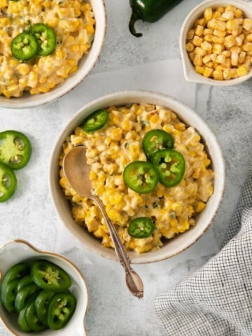 A spoon in a bowl of cream jalapeno corn.