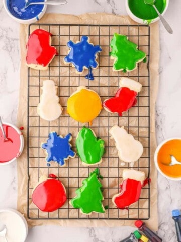 Twelve decorated christmas sugar cookies on a cooling rack.