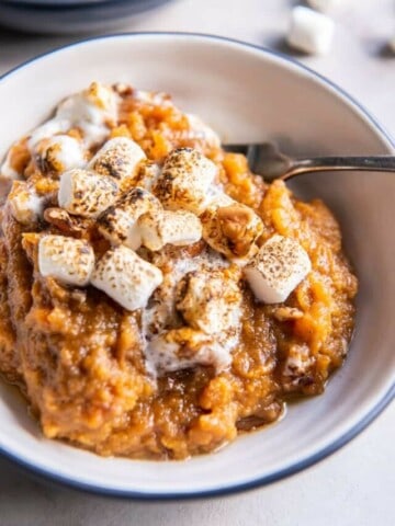 A close up view of a single serving of sweet potato casserole in a bowl with a fork.