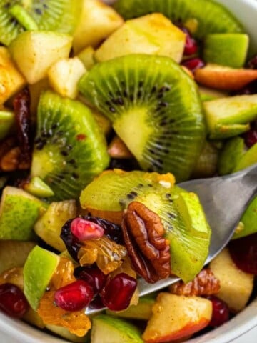 taking a bite out of kiwi and apple salad with a fork.