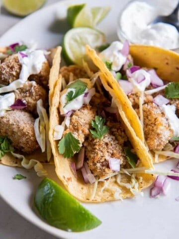 serving air fryer fish tacos in a corn tortilla with toppings.