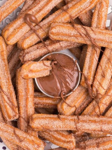 drizzling melted nutella over air fryer churros on a plate