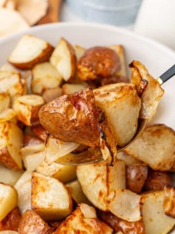 using a spoon to scoop up air fried potato and onions