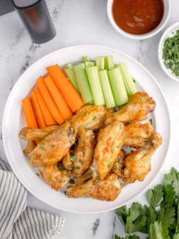 air fryer chicken wings with baking powder on a plate with cut veggies