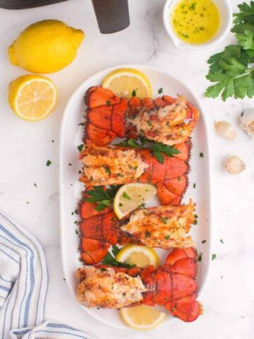 Air fried lobster tails lined up on a platter with garnish.