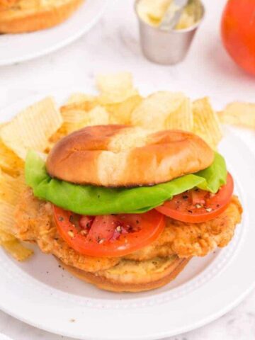 Fried pork chop sandwich with lettuce and tomato.