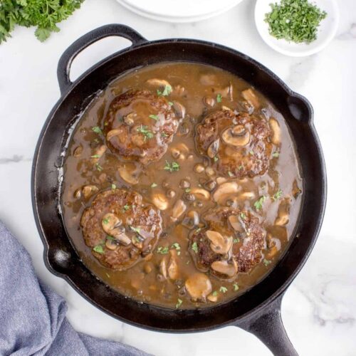 simmered homemade salisbury steak in a cast iron skillet