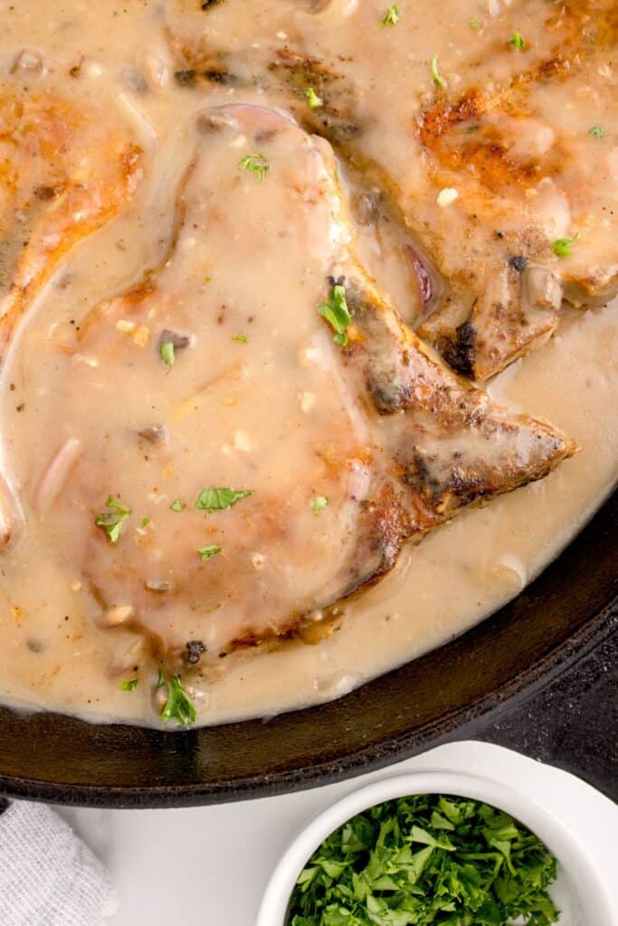 close up of pork in a pan with onion gravy 