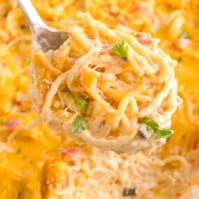 using a slotted spoon to serve chicken spaghetti with rotel onto a plate