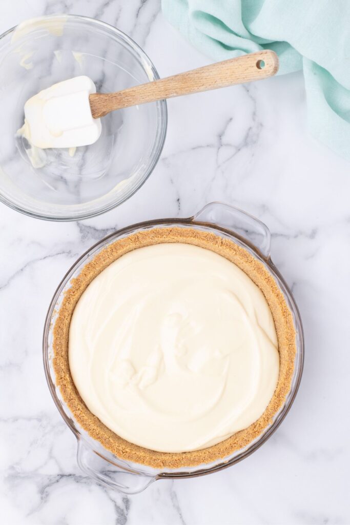 pouring key lime pie filling into cooked graham crust 